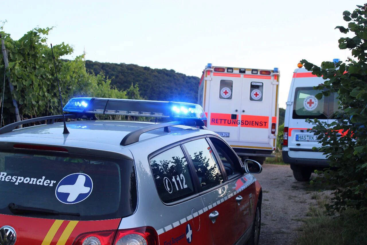 Fahrzeug der First Responder mit Blaulicht im Einsatz, davor zwei Rettungswagen des Roten Kreuzes